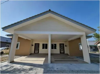 Front elevation of a completed single-storey bungalow built by RumahHQ — symmetrical gable roof with cream board soffit, two wrought grille doors under the carport, tiled entrance steps, and a neatly finished concrete slab
