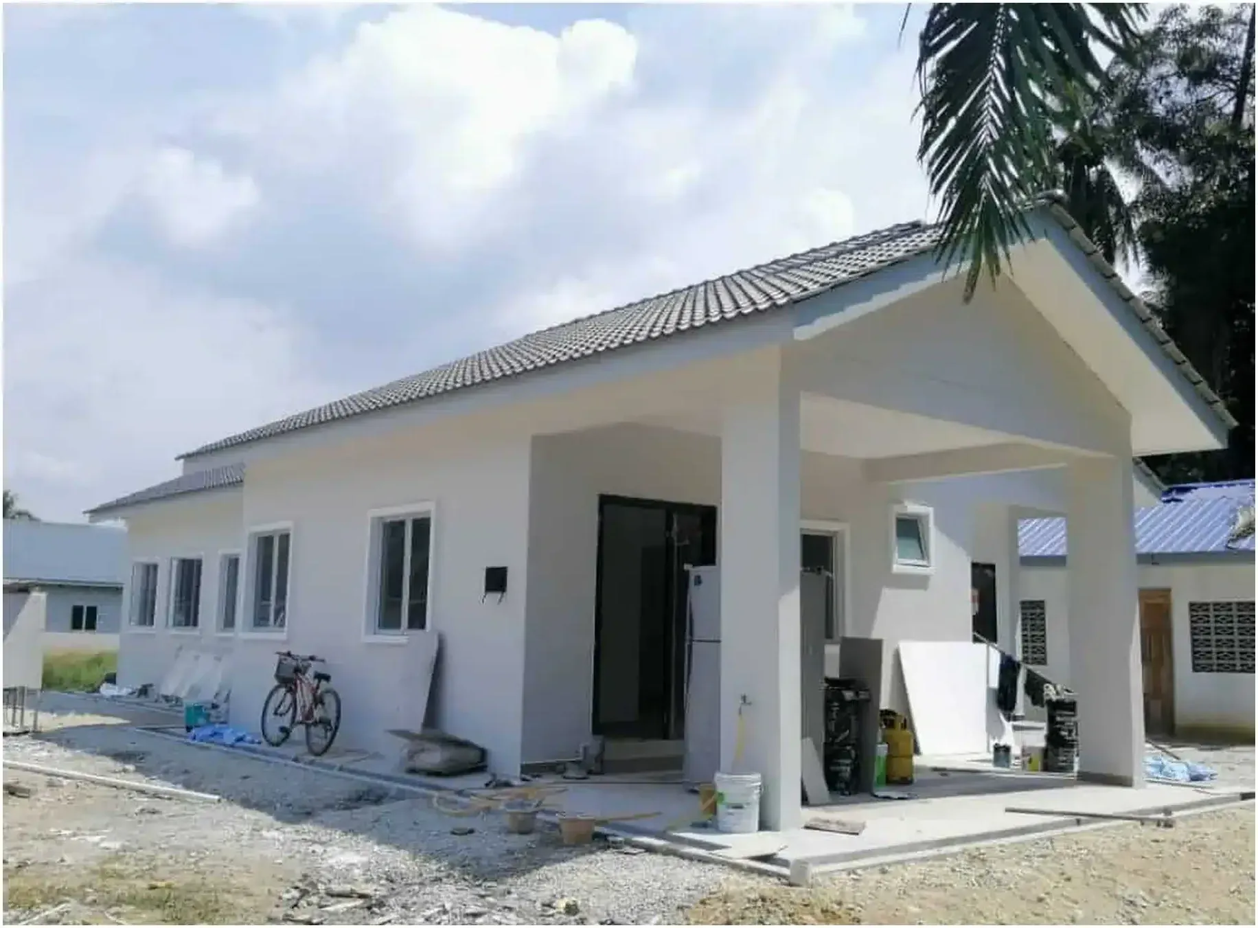 Rumah setingkat berplaster putih hampir siap, bumbung genting terpasang dan anjung depan sudah berdiri