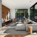 Modern living room with gray sofa, wood accents, and open patio doors leading to outdoor dining area.
