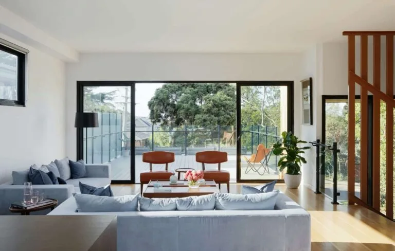 Modern living room with large windows, stylish furniture, and outdoor patio view for a bright, inviting space.