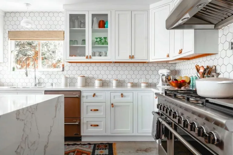 Modern kitchen with white cabinets, stainless steel appliances, and hexagonal tile backsplash. Bright and stylish design.