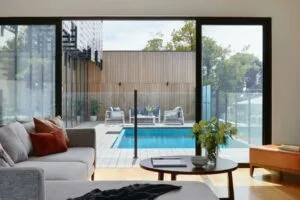 Modern living room overlooking stylish outdoor pool and patio through glass doors.